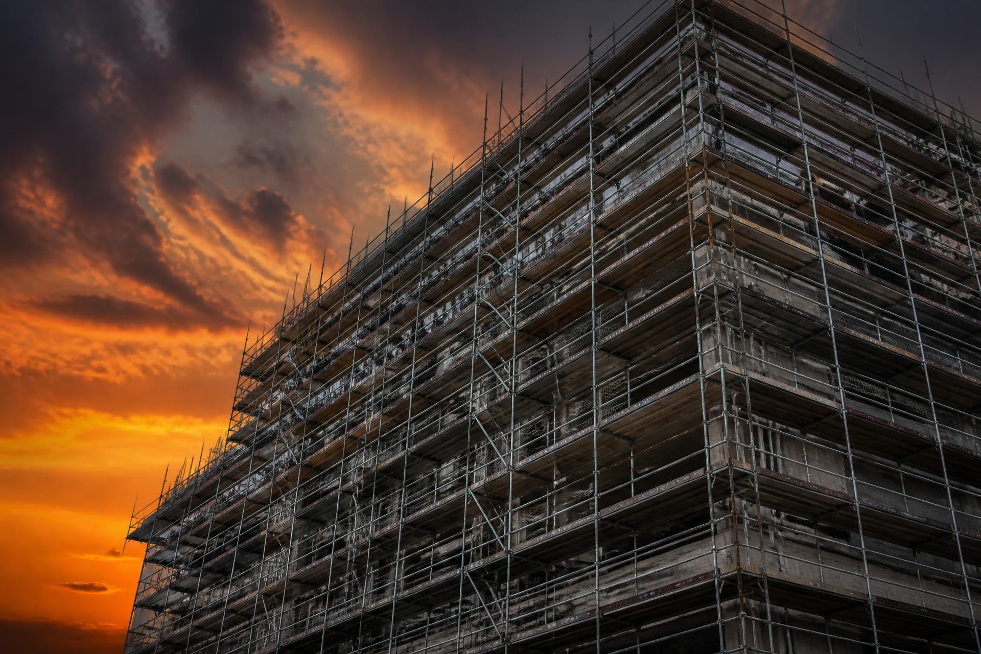 Scaffolding tower silhouetted against a dramatic sunset on a commercial site